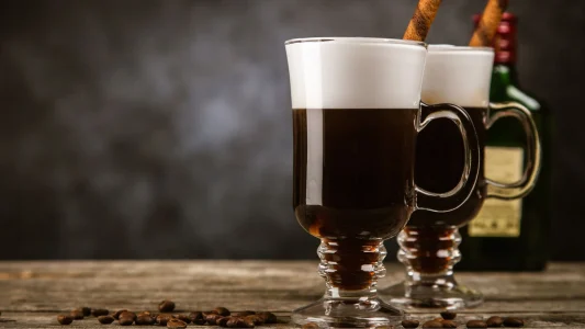 Talpas, füles poharakban kettő ír kávé. Fekete kávé tetején hófehér hab.